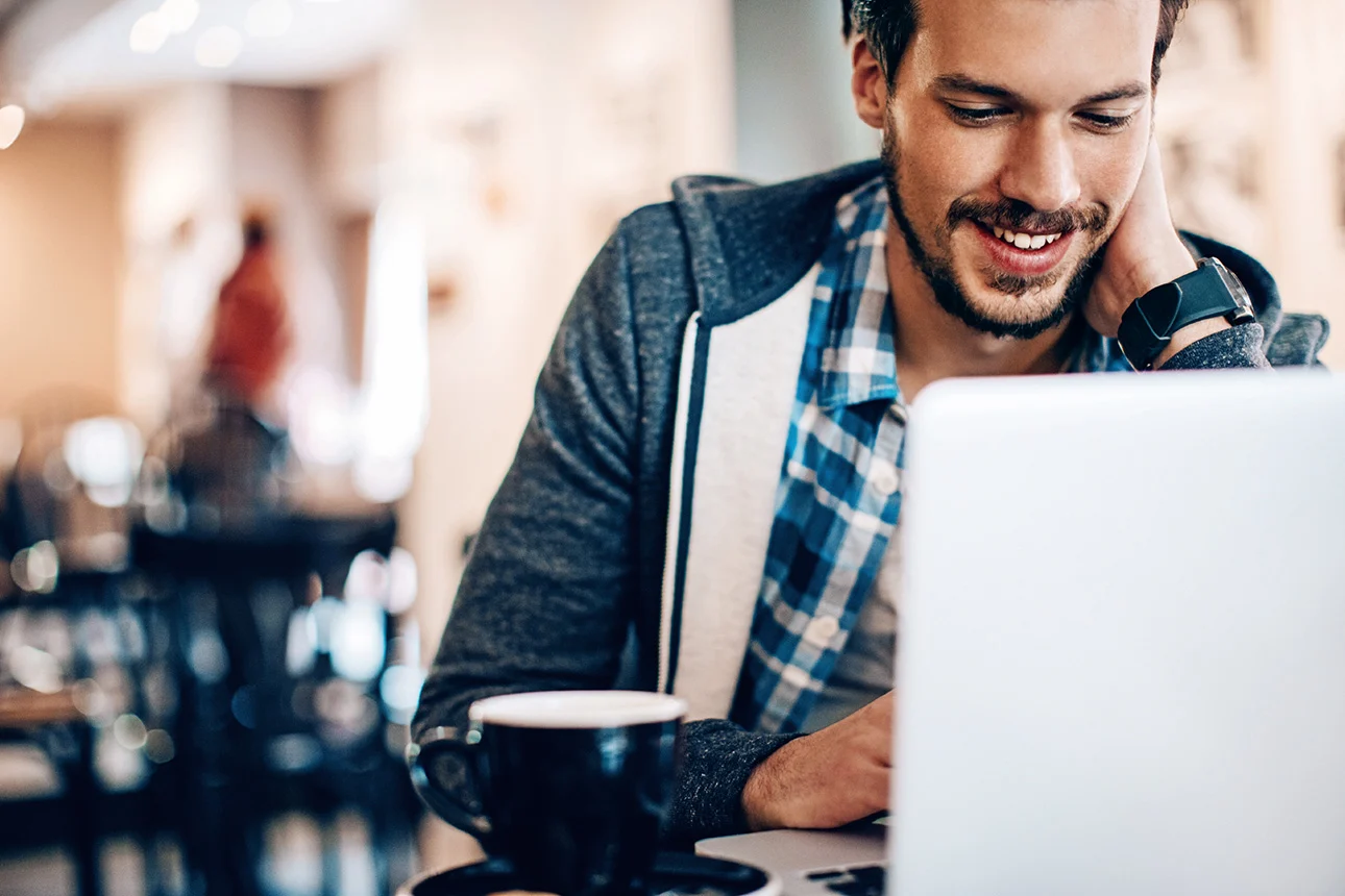 Ein Mann sitzt an einem Laptop in einem Café