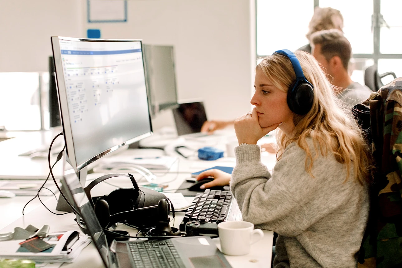 Frau mit Headset arbeitet konzentriert am Computer im Büro