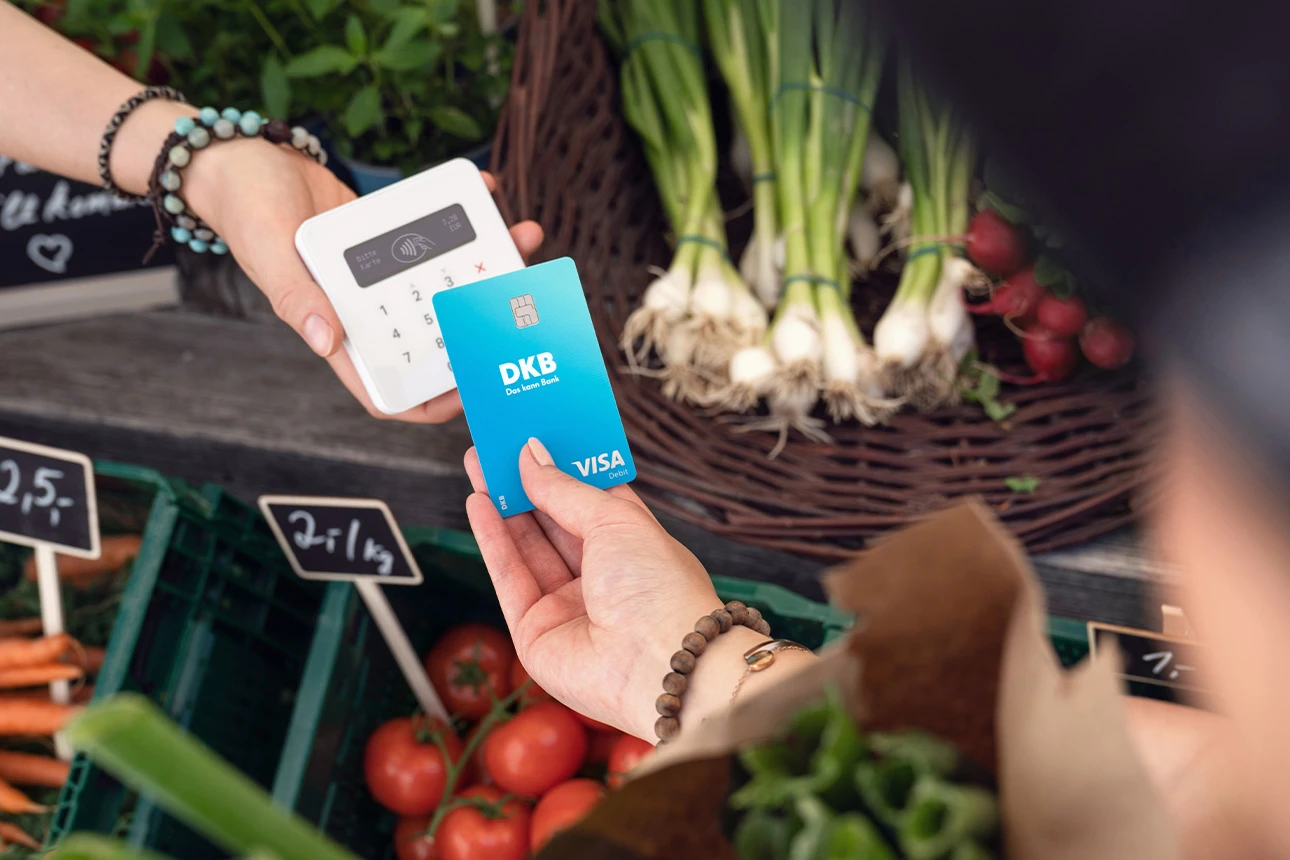 Person bezahlt seinen Einkauf kontaktlos mit der Visa Debitkarte