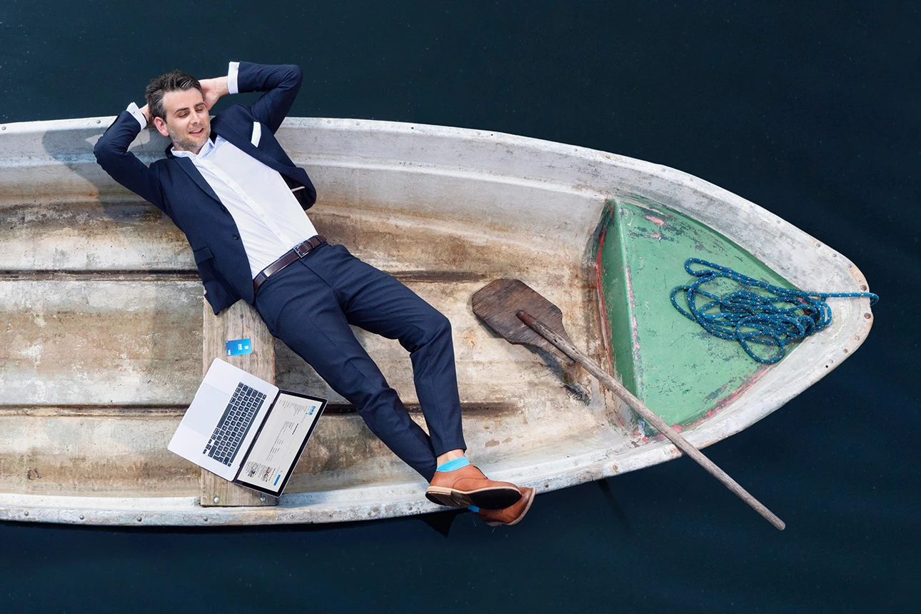 Mann auf Boot mit Laptop und Visa Debitkarte
