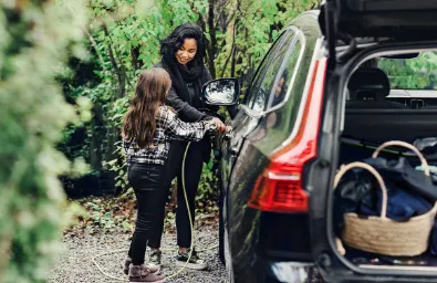 Eine Frau lädt gemeinsam mit einem Kind ein Elektroauto.