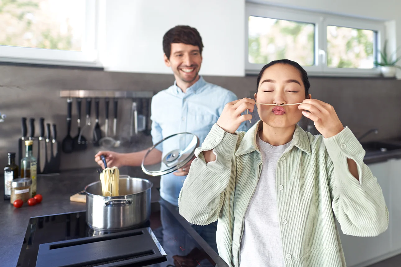 Eine Frau und ein Mann kochen Nudeln