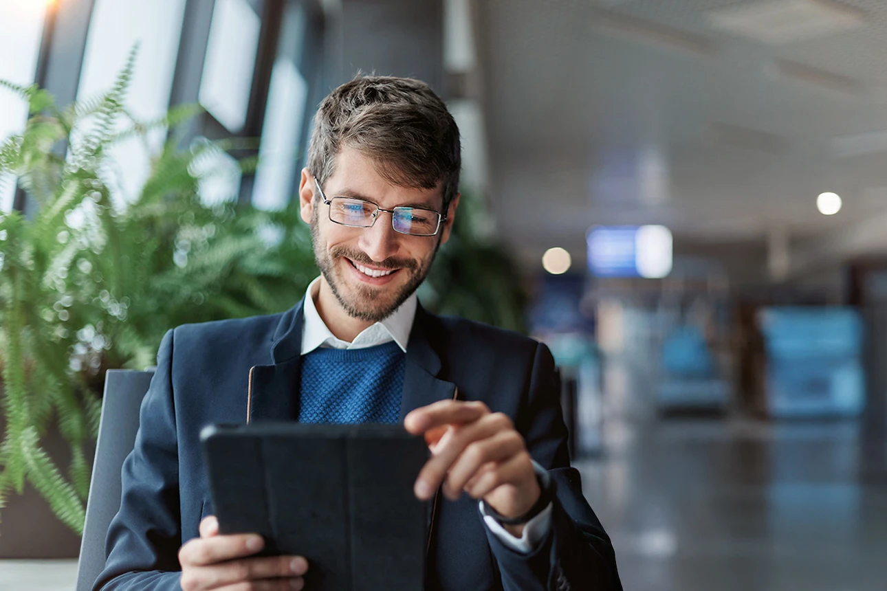 Ein Mann sitzt in einem Stuhl mit einem Tablet in der Hand