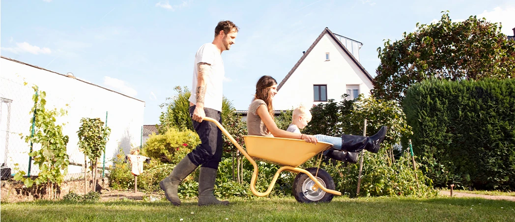 Mann mit Frau und Kind in Schubkarre