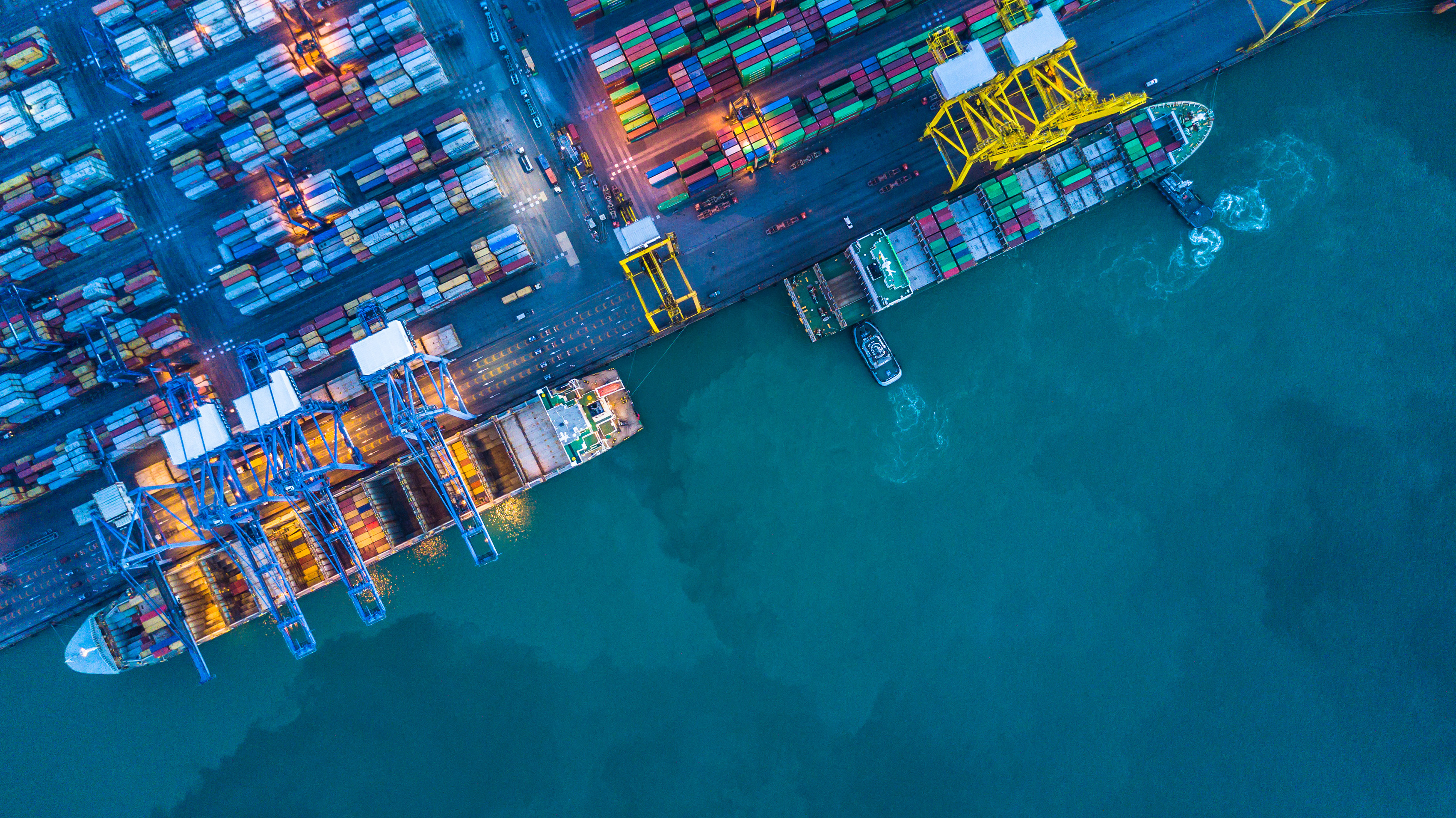 Aerial view of a container cargo ship by a dock.