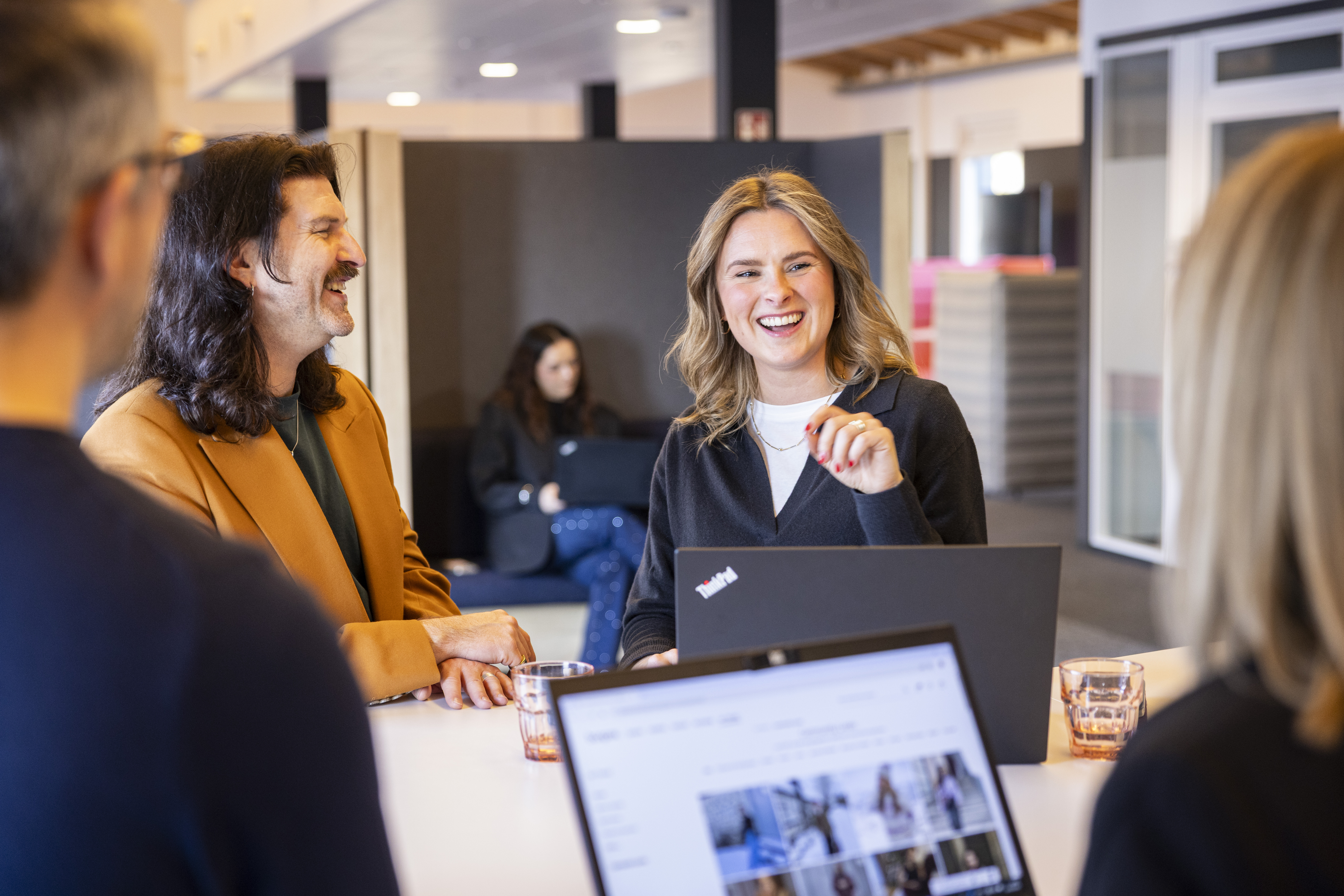 Eine Gruppe von fünf Personen steht lächelnd nebeneinander vor einer grauen Wand.