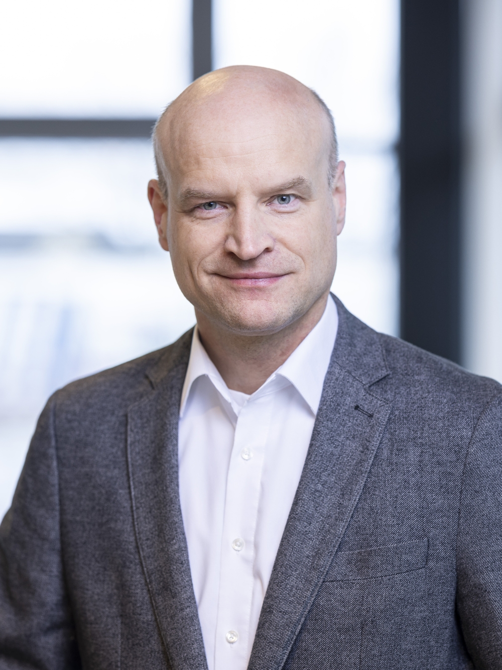 Nicolai Johannsen in a grey suit and white shirt in front of a bright office window.