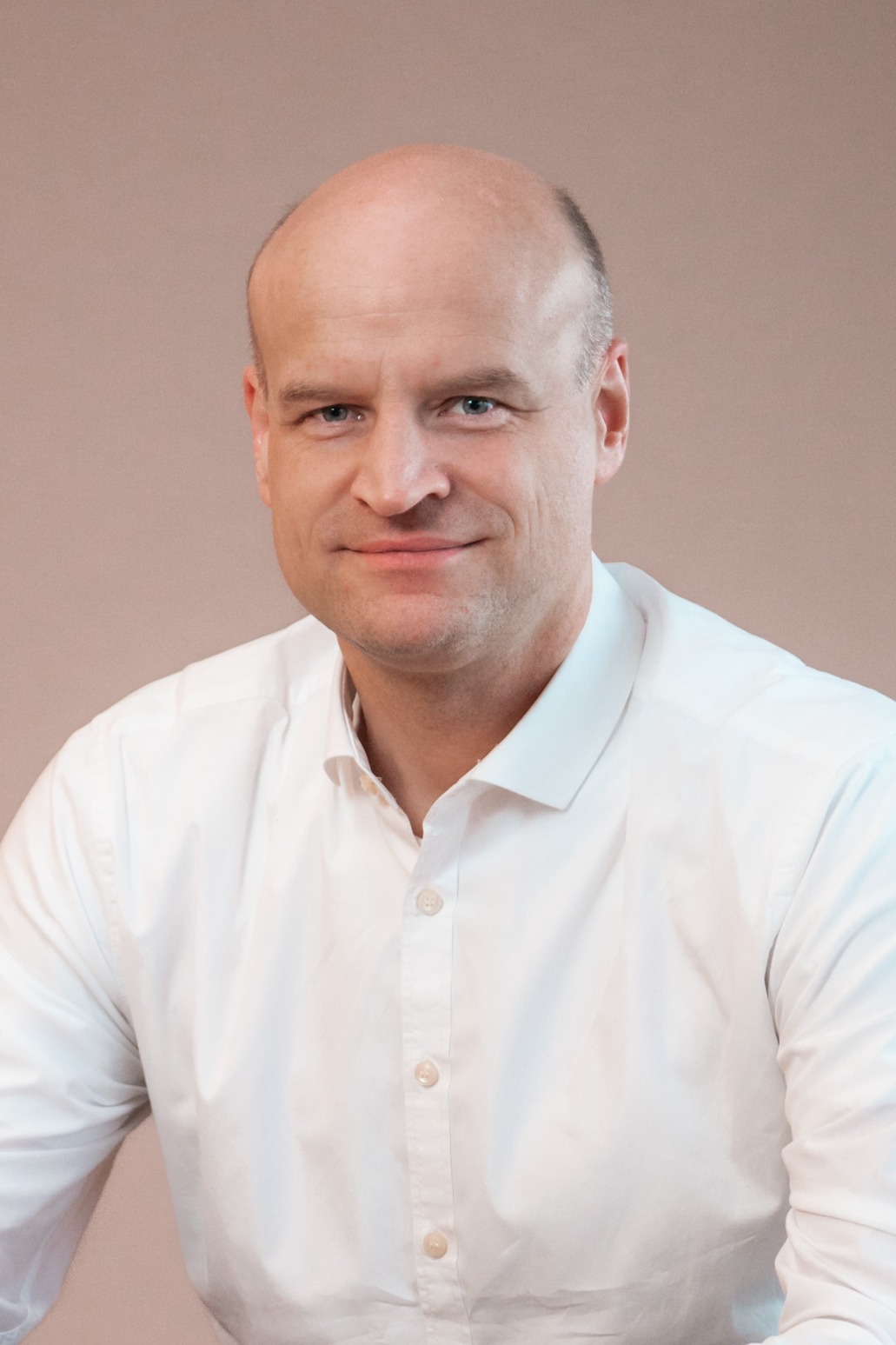 Nicolai Johannsen in weißem Hemd vor neutralem Hintergrund.