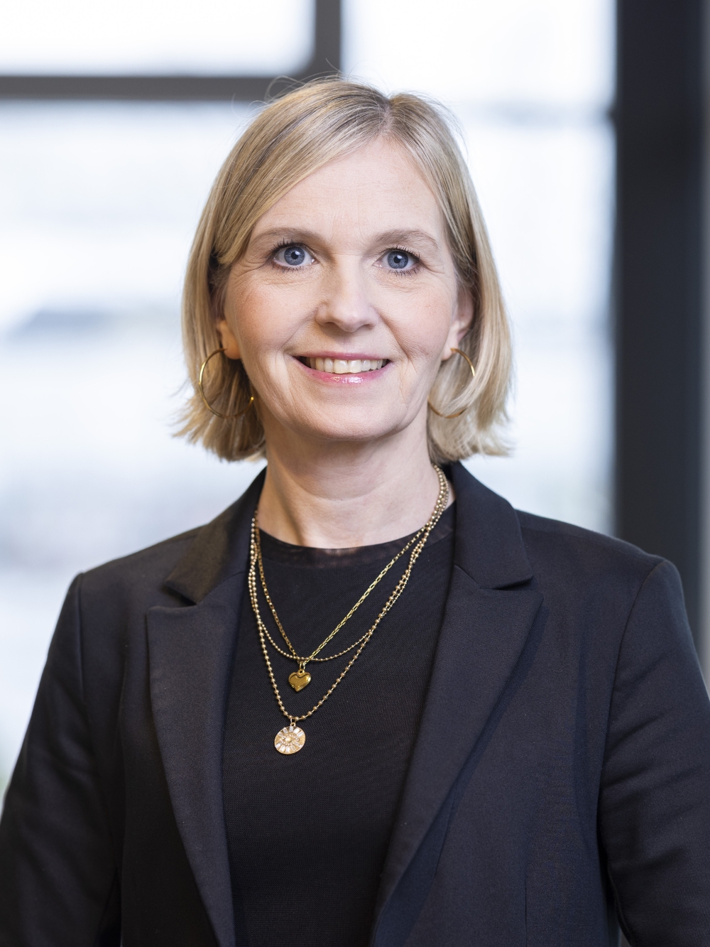 Carolin Klar in business dress smiles in front of a bright background.