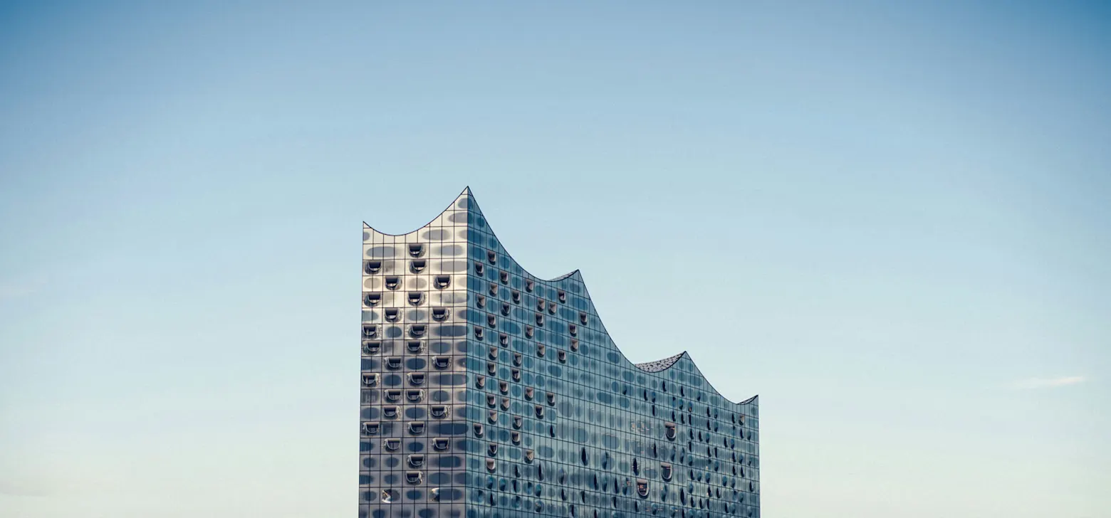 A striking building with a wavy facade rises into the clear blue sky.