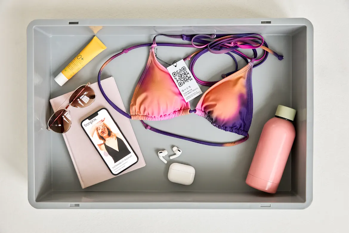Bikini-Oberteil, Sonnenbrille, Smartphone und Sonnenschutz in einer Schale: Bereit für den Strand.