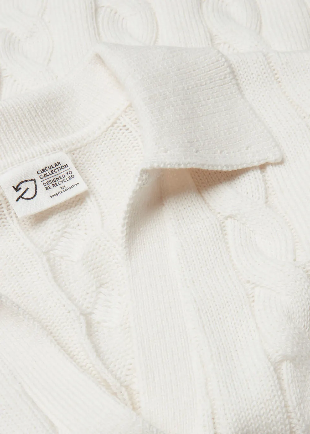 Beige knit sweater with collar and label.