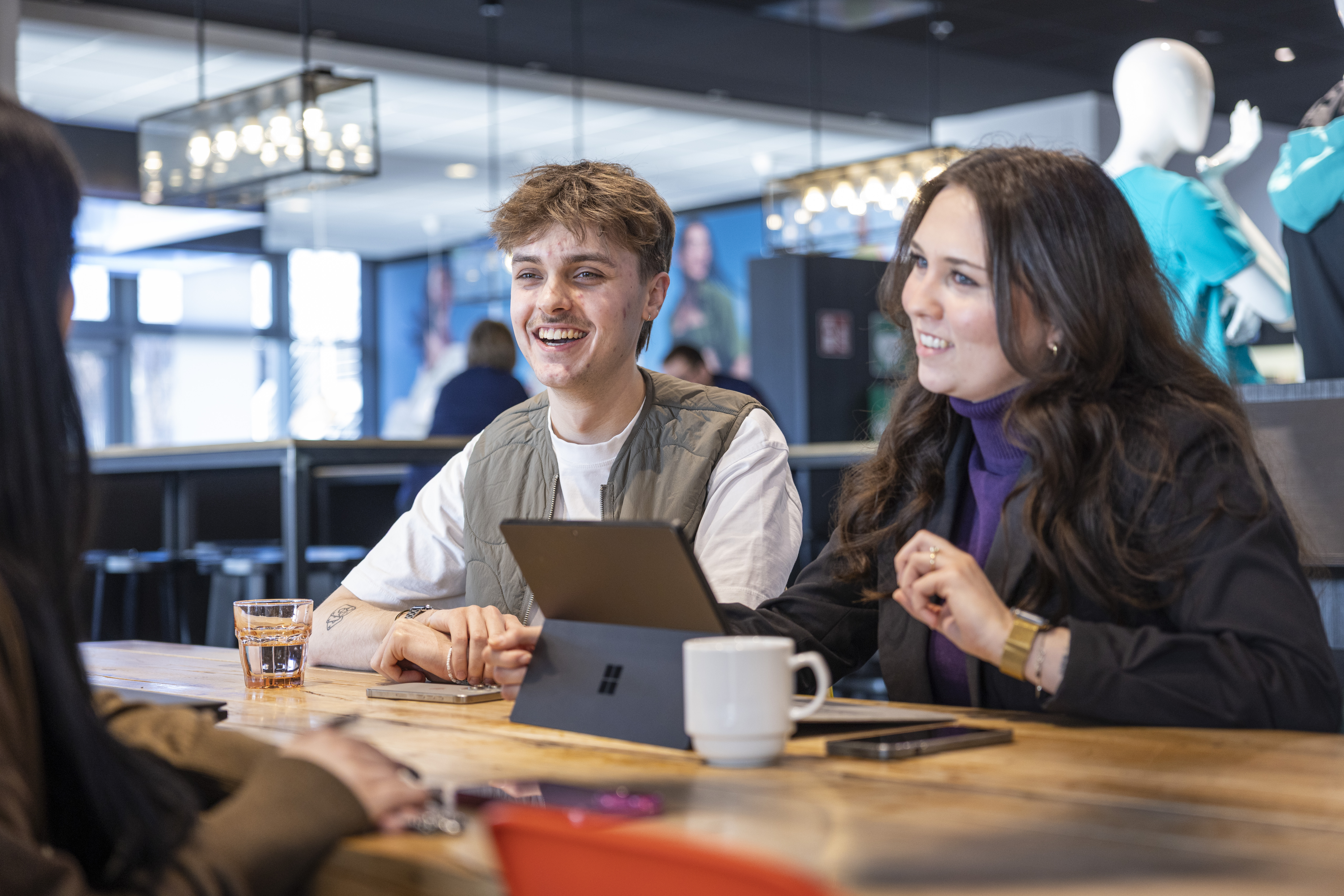Eine vielfältige Gruppe von vier Personen posiert selbstbewusst vor einem grauen Hintergrund.