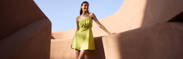 Ein luftiges, leuchtend gelbes Sommerkleid mit schmalen Trägern wirbelt elegant im warmen Wüstenwind.