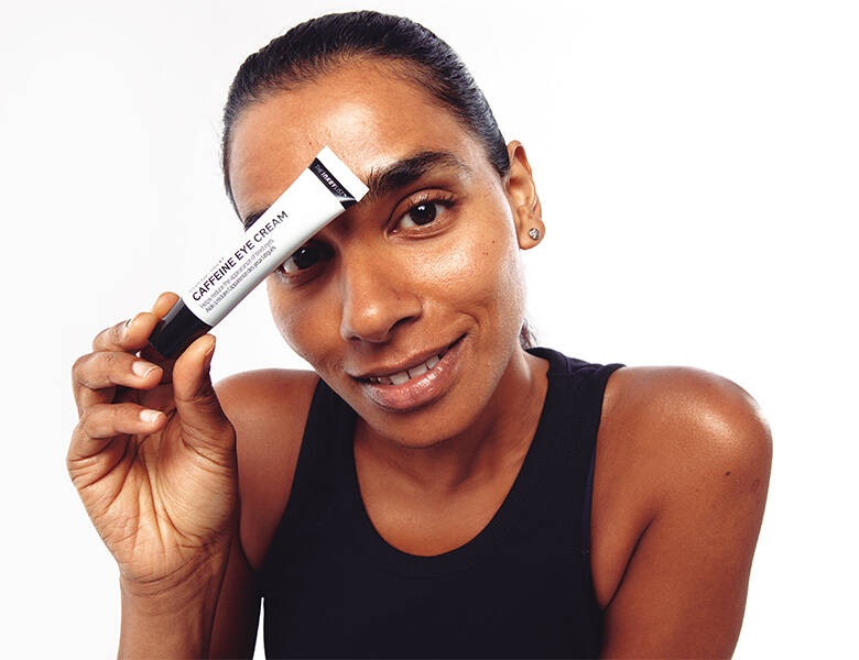 Her ses en hvid baggrund med en kvinde, som holder et The INKEY List produkt op foran det ene øje.