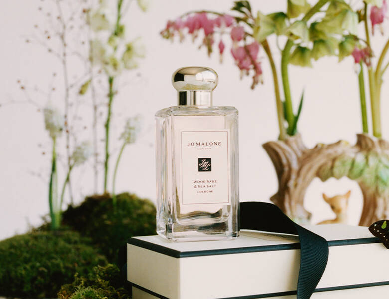 Her ses en hvid Jo Malone London cologne på en hvid baggrund med natur og bøger. 