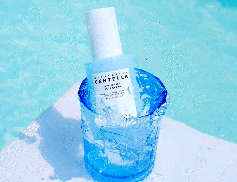 Her ses et blåt Skin1004 produkt i et blåt glas. Baggrunden er en pool.