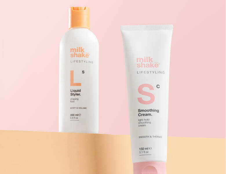 Her ses et billede med to hårprodukter fra milk_shake placeret mod en lyserød baggrund. På produkterne står teksten “milk_shake LIFESTYLING”, “Liquid Styler” og “Smoothing Cream”. Produkterne er i hvide emballager med orange og lyserøde detaljer.