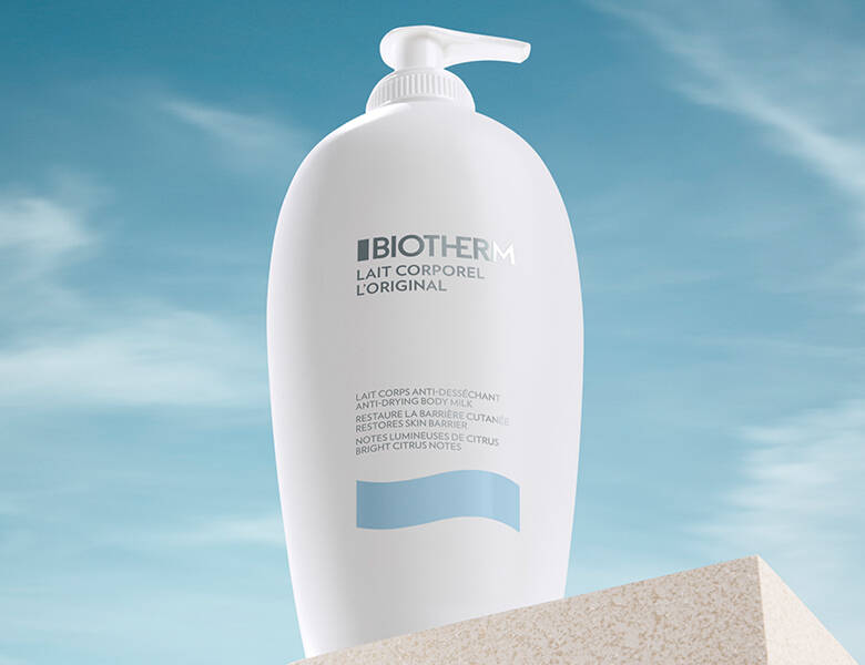 Her ses et hvidt Biotherm produkt stående på en sandfarvet sten med en blå himmel som baggrund.
