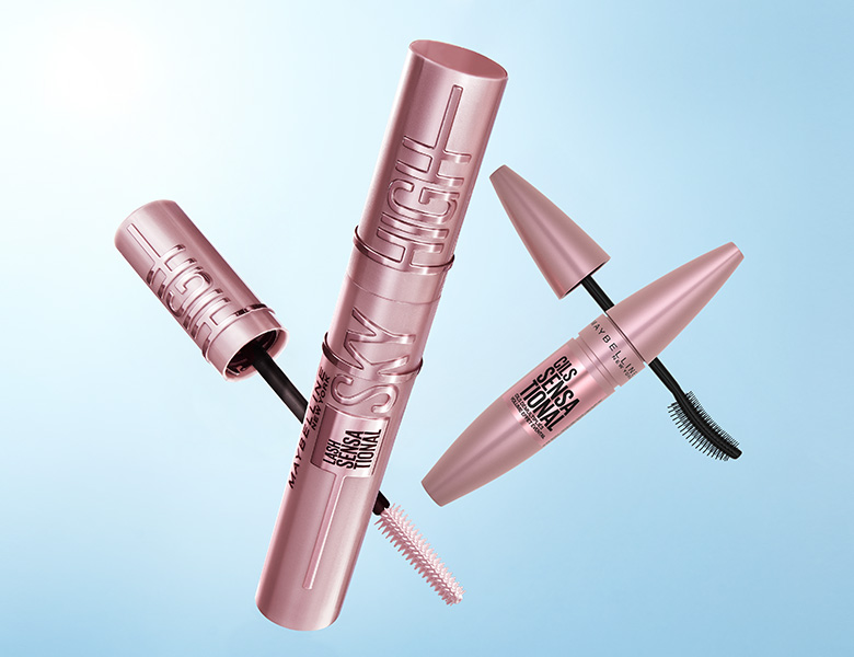 Her ses et billede med flere mascaraprodukter placeret mod en blå baggrund. På produkterne står blandt andet “SKY HIGH” og “SENSATIONAL”. Nogle af mascarerne er åbne, så børsterne er synlige.