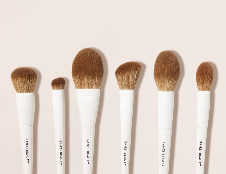 Her ses seks makeupbørster på en lys baggrund. 