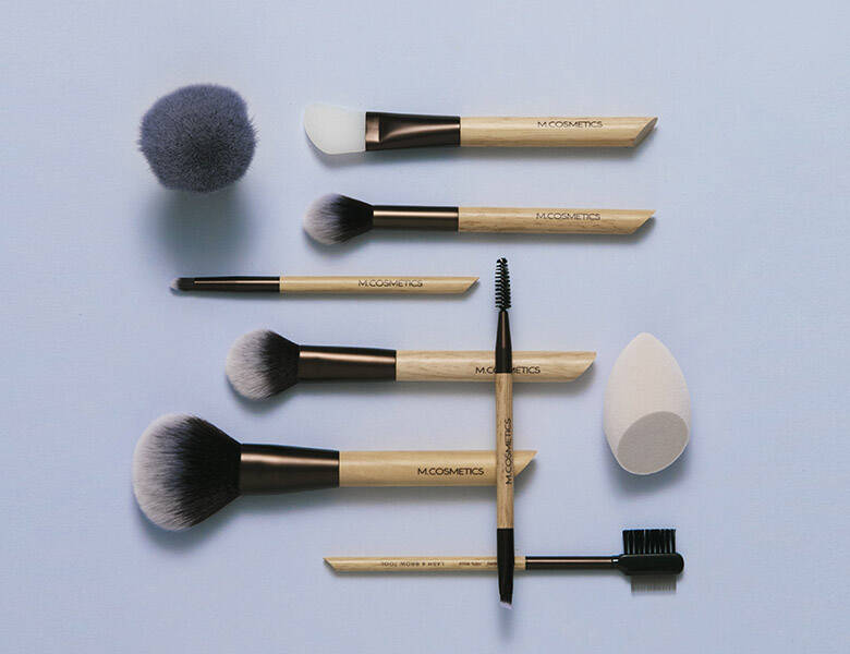 Her ses en masse forskellige M.Cosmetics produkter på en lilla baggrund. 