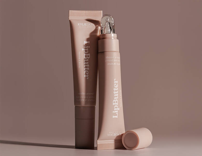 Her ses en brun-lyserød baggrund med to læbeprodukter. 