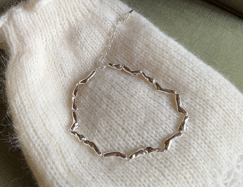 Her ses en halskæde, som ligger på en hvid strik.