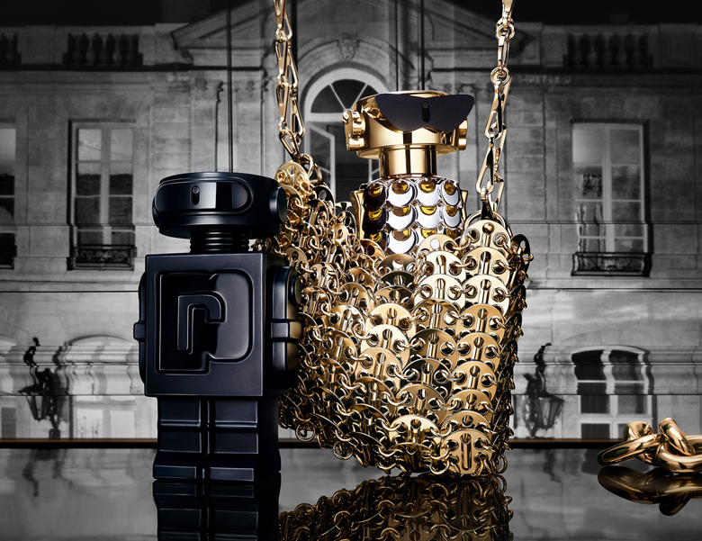 Her ses et billede med to parfumeflakoner placeret side om side mod en baggrund med en bygning. Den ene flakon er sort og formet som en figur, og den anden er guldfarvet med kædedetaljer.