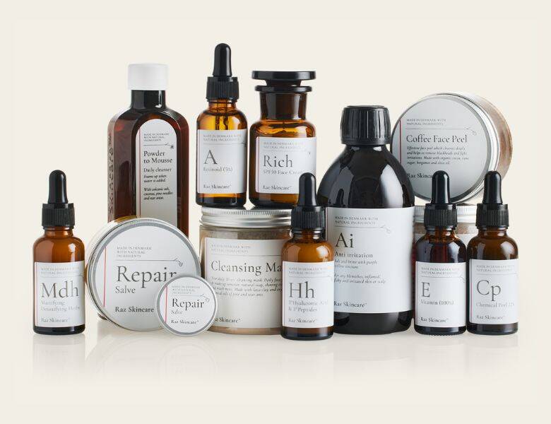 Her ses en masse Raz Skincare produkter stående i flere lag. Baggrunden er meget lysegul.