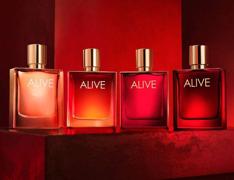 Her ses fire røde Alive parfumer på række. Baggrunden er også rød.