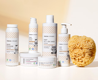 Matas Striber babypleje med babypudder, baby salve, alt-i-en vask, babyolie, mavecreme og baby SOS multi balm står samlet ved siden af en gul natursvamp.