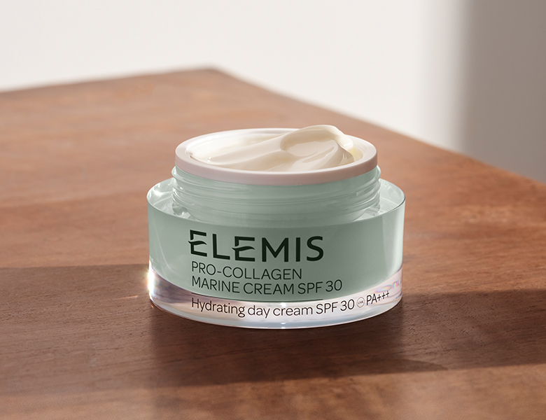 Her ses en ELEMIS ansigtscreme i en krukke på et træbord.