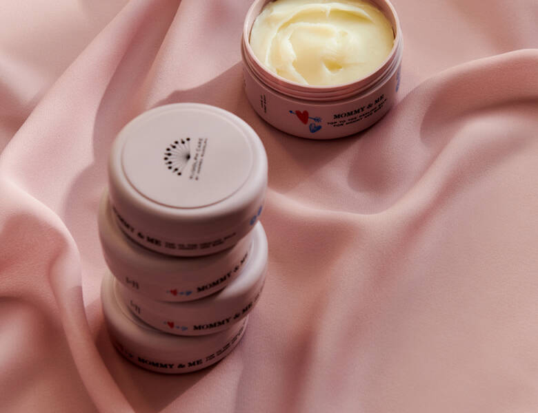 Her ses nogle produkter stablet på et lyserødt materiale. Ved siden af ses også et åbent produkt.