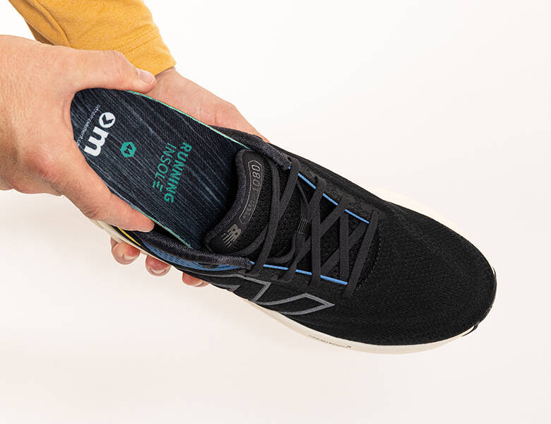 Her ses en hvid baggrund. Der er to hænder - den ene holder en sko og den anden er i færd med at putte en sål i skoen.