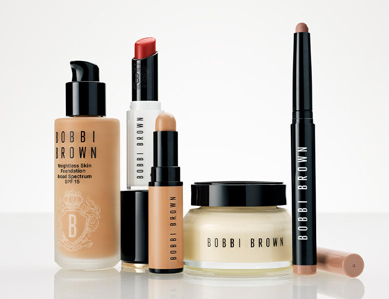 Her ses et billede med en række makeup- og hudplejeprodukter fra Bobbi Brown mod en lys baggrund. Produkterne omfatter blandt andet Weightless Skin Foundation SPF 15, en læbestift, en concealer, en ansigtscreme i krukke og en øjenskygge- eller makeupstift. Produkterne er opstillet samlet med fokus på brandets bestsellere.