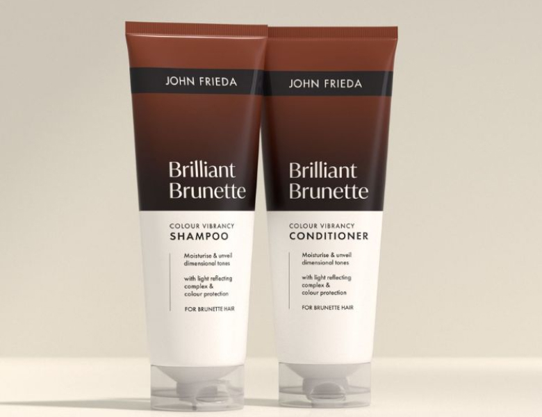 Her ses et billede med hårplejeprodukter fra John Frieda placeret mod en lys baggrund. På produkterne står teksten “Go Blonder”, og serien indeholder shampoo, conditioner og spray. Nederst står teksten “COLOUR”.
