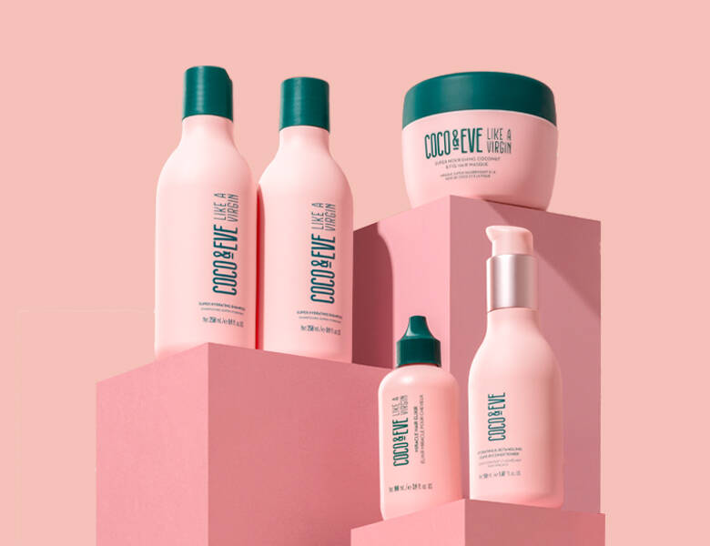 Her ses en lyserød baggrund med fem lyserøde og grønne Coco & Eve produkter. 