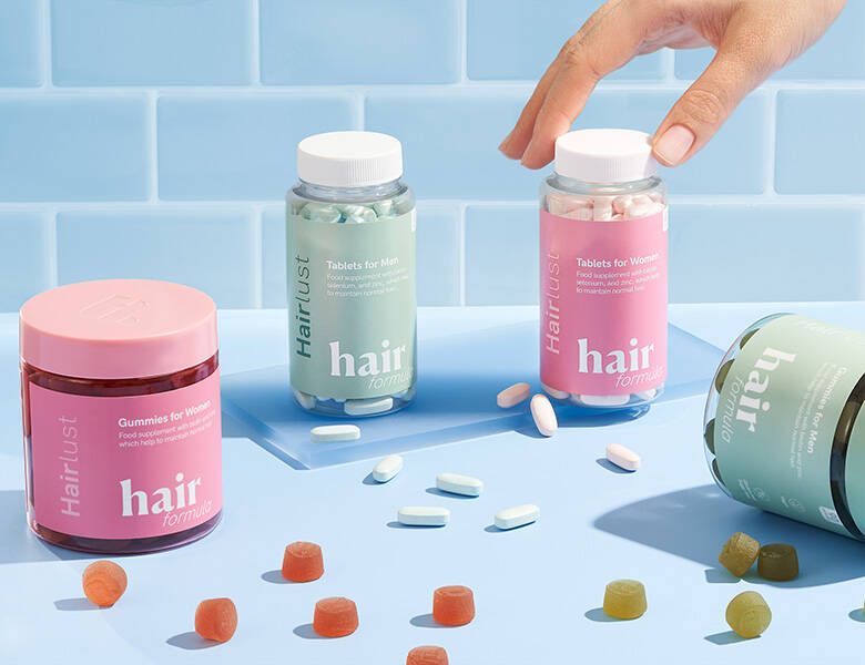 Her ses fire farverige Hairlust produkter på et blåt badeværelse.