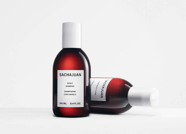 Her ses et billede med to shampoo-flasker fra SACHAJUAN placeret mod en lys baggrund. På flaskerne står teksten “SACHAJUAN Scalp Shampoo”. Den ene flaske står oprejst, mens den anden ligger ned.
