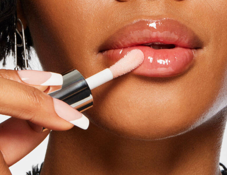 Her ses et close-up billede af en kvinde, som er ved at tage lipgloss på sine læber. 