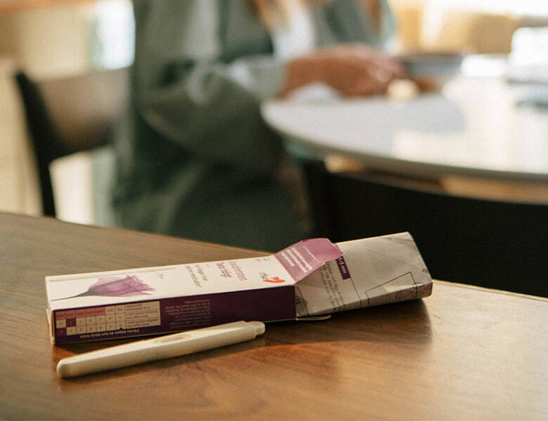 Her ses en åben pakke med graviditetsteste. Den ligger på et træbord.