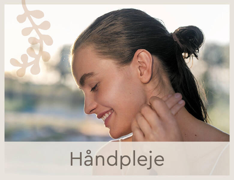 Her ses en glad kvinde. Hun holder om sin højre hånd med sin venstre. 