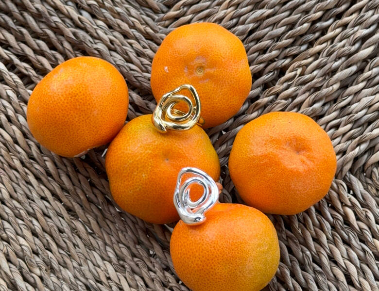Her ses to ringe - en i guld og en i sølv. De ligger i en kurv med klementiner. 