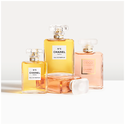Her ses et billede med flere parfumeflakoner fra Chanel placeret samlet mod en lys baggrund. På flakonerne står teksten “N°5 CHANEL PARIS EAU DE PARFUM” samt “COCO MADEMOISELLE CHANEL PARIS”. Flakonerne er i gyldne og lyserøde nuancer med transparente låg.