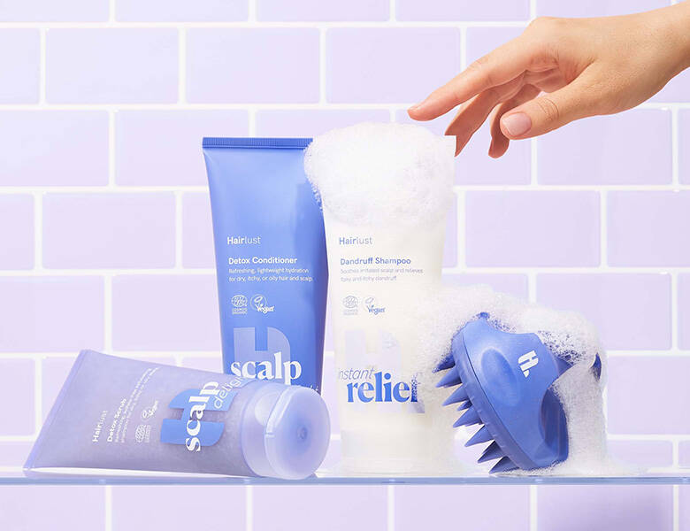 Her ses Hairlust produkter, hovedsageligt i lilla, på nogle lilla klinker og med sæbeskum. 