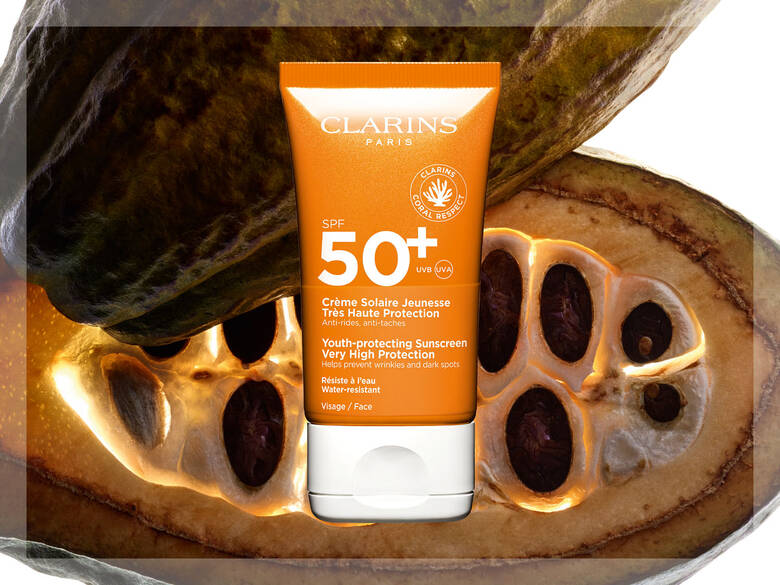 Her ses en orange Clarins solcreme på en brun bønne.