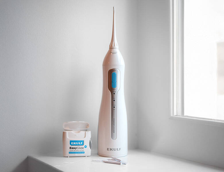 Her ses to hvide og blå produkter fra Ekulf. De står i en hvid vindueskarm med en hvid væg bagi. 