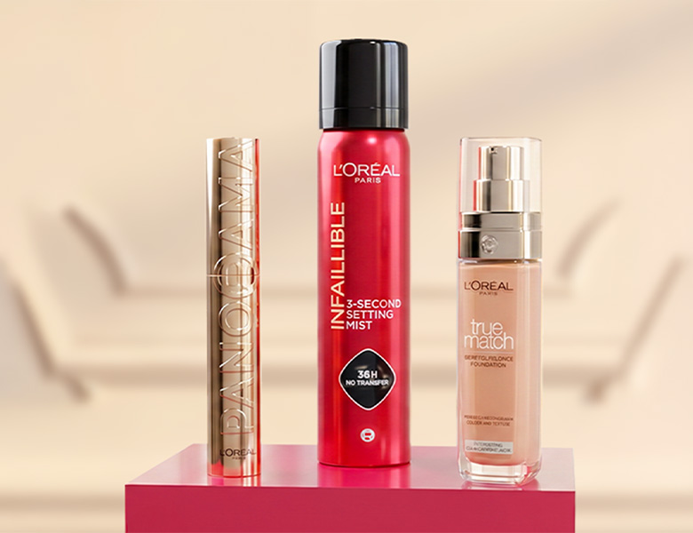 Her ses tre L’Oréal Paris makeupprodukter på en pink sokkel: Panorama Mascara, Infaillible 3-Second Setting Mist og True Match Foundation.