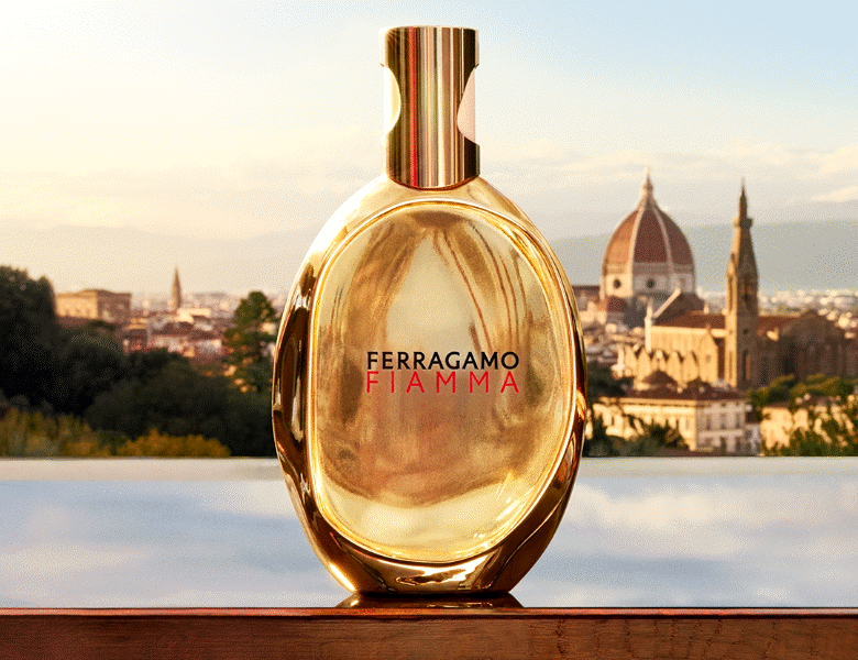 Her ses en parfume med guldflakon; Ferragamo Fiamma. Bagved er der vand og en kirke i sollys.